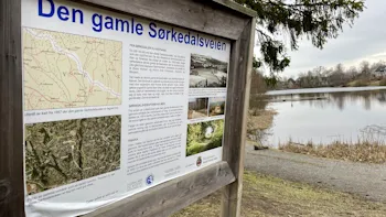Fremdeles noe is på Holmendammen mandag 8. april, men både svanene og castingfolket er på plass. Skiltet forteller historien om den gamle Sørkedalsveien, som gikk forbi.